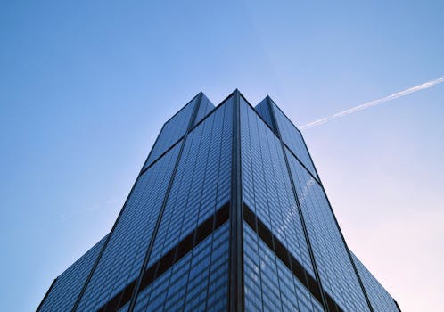 Low angle shot of a modern skyscraper in Chicago with a clear sky and contrails visible.